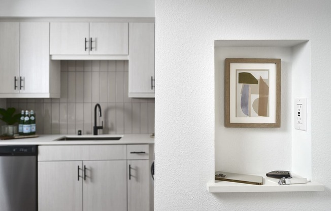 a kitchen with white cabinets and a picture on the wall