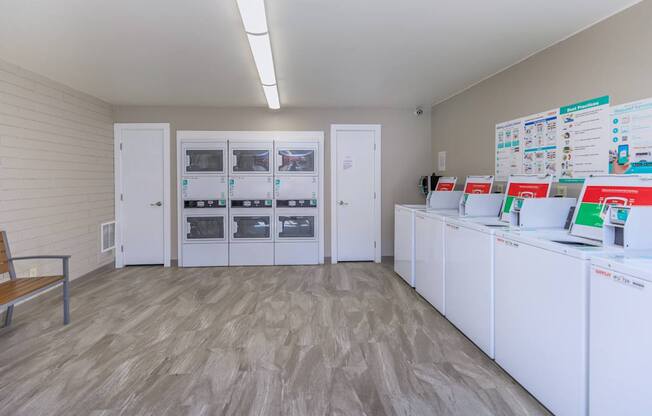 A room with white cabinets and a wall of fridges.