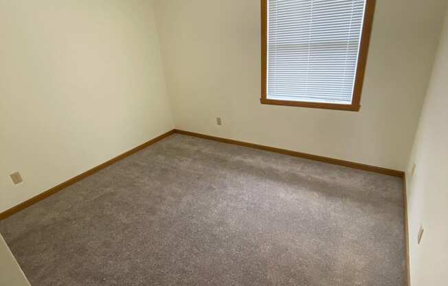 a room with a carpeted floor and a window. Fargo, ND Sheyenne Terrace