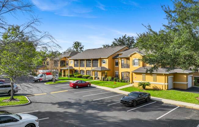 a large yellow house with cars parked in a parking lot