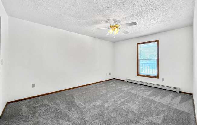 A room with a ceiling fan and a window with blinds.