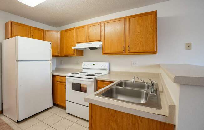 A kitchen with a white refrigerator, white stove, and a white sink. Fargo, ND Summit Point