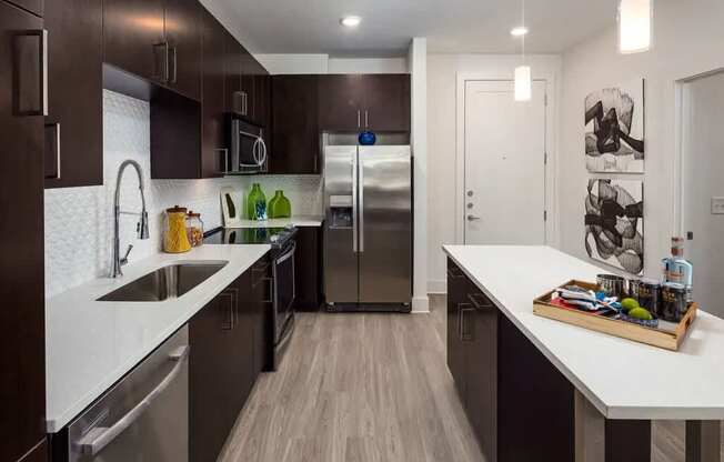 A modern kitchen with dark brown cabinets and stainless steel appliances.
