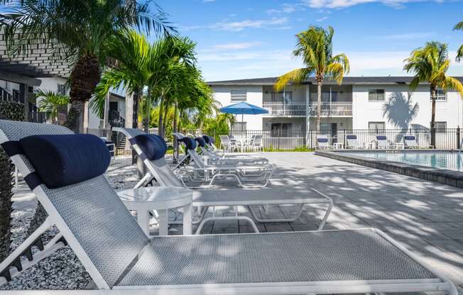 a pool with chairs and tables and a building in the background