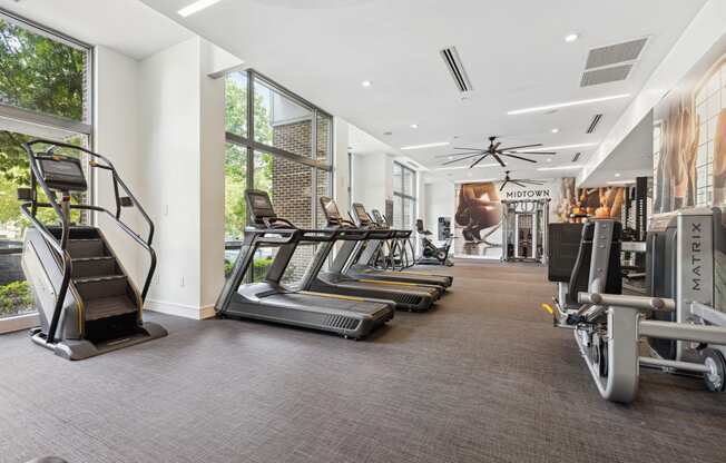 a room filled with cardio equipment and large windows