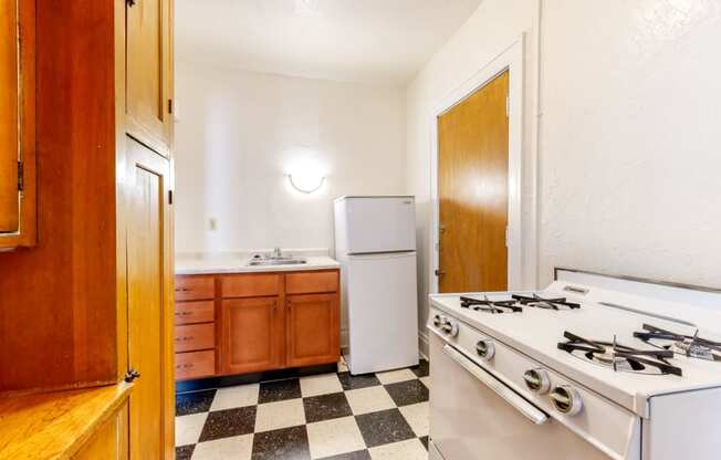 Kitchen with White Appliances and Retro Checkered Flooring at The Park Apartments in Minneapolis, Minnesota