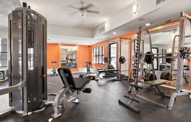 a gym with weights and cardio equipment and a ceiling fan