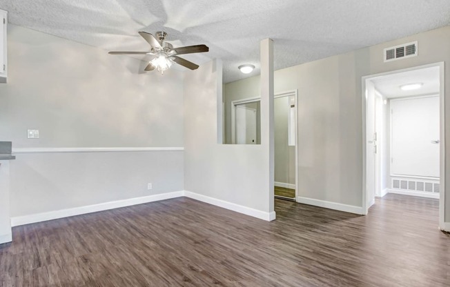 an empty living room with white walls and a ceiling fan