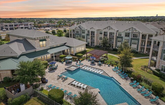 A large outdoor swimming pool surrounded by lounge chairs and umbrellas.