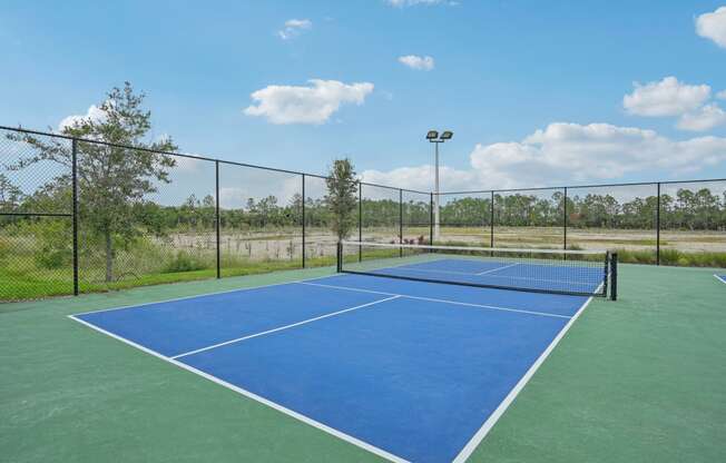 a blue and green tennis court with a fence around it