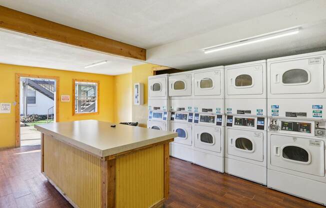 A row of washing machines are lined up in a laundromat.