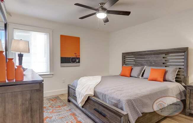 A bedroom with a queen size bed and a ceiling fan