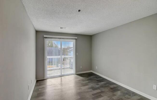 an empty living room with a sliding glass door to a balcony at The Sapphire, Georgia