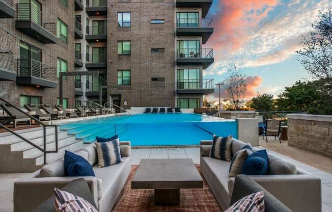 an outdoor lounge area with couches and a coffee table in front of an apartment building