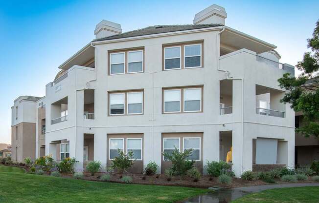 A large, modern apartment building with a pond in front.