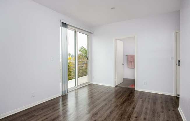 a living room with white walls and wooden floors and sliding glass doors