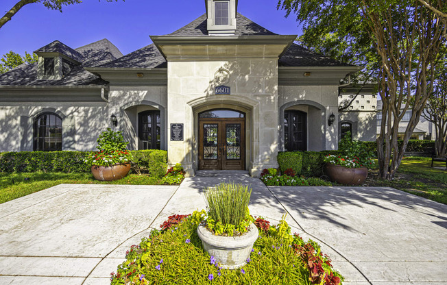 the front of a house with a driveway and potted plants