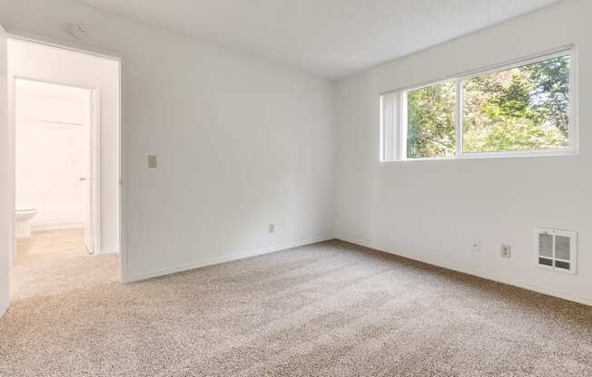 an empty room with a window and a door to a bathroom