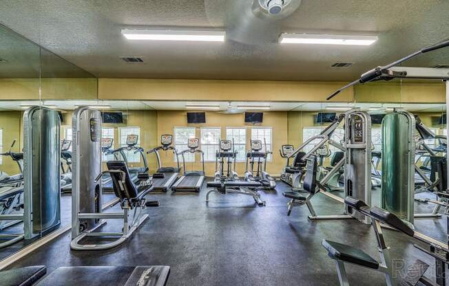 a gym with cardio equipment and weights on the floor