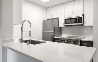 A kitchen with a sink, stove, and microwave.