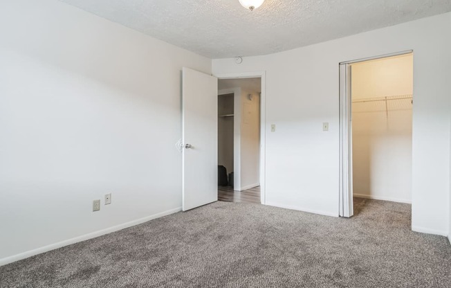 an empty bedroom with white walls and a door to a closet