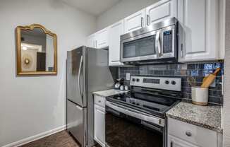 an updated kitchen with stainless steel appliances and white cabinets