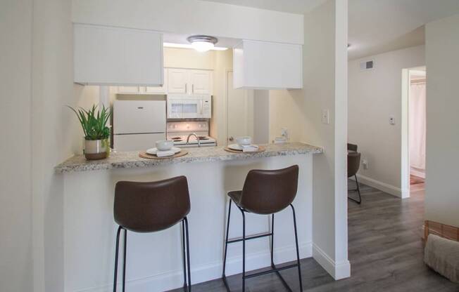 This is a photo of the breakfast bar and kitchen in the 558 square foot 1 bedroom, 1 bath model apartment at The Summit at Midtown Apartments in Dallas, TX.