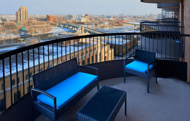 A balcony with a black railing has two chairs and a table.