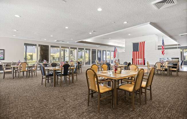 A large room with tables and chairs and flags hanging from the ceiling.