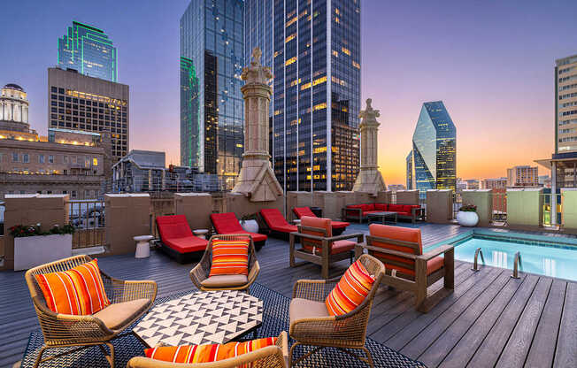 A rooftop patio with chairs and a table with a view of the city.