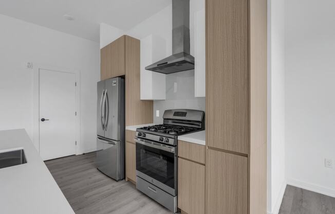 A modern kitchen with a stainless steel refrigerator, oven, and range hood at The Franklin Marlboro Apartments, Marlboro