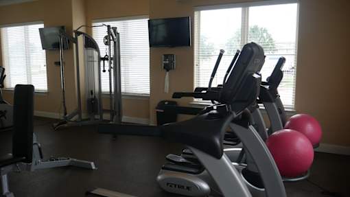 A gym with a variety of equipment including a stationary bike, a rowing machine, and a treadmill.