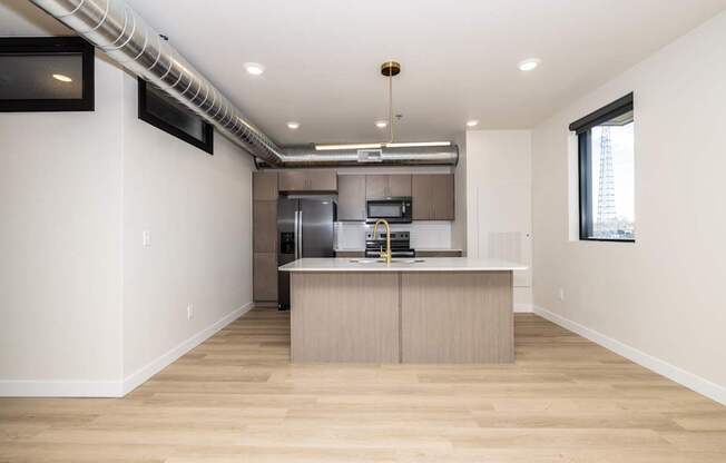 A modern kitchen with wooden floors and stainless steel appliances.
