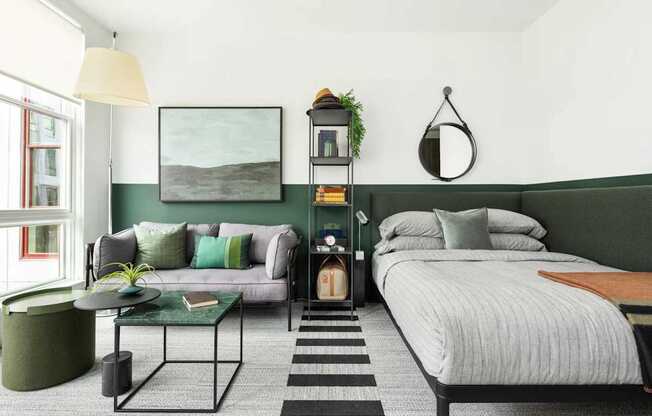 A bedroom with a bed, a couch, a table, and a plant.