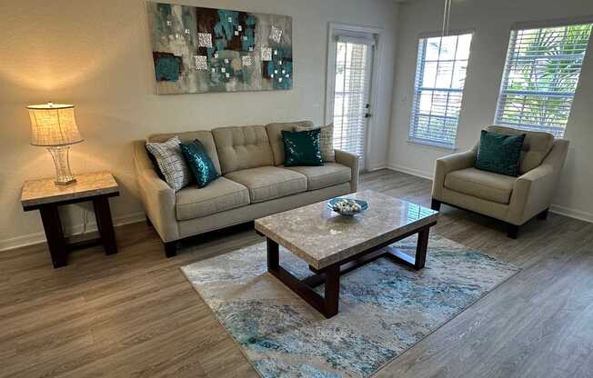 A living room with a couch, chair, and a painting on the wall.
