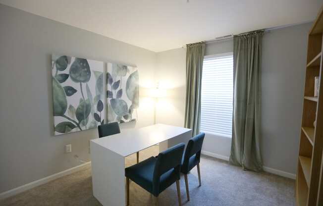 a dining room with a white table and chairs and a painting on the wall at Evergreen Luxury Apartments, Merrillville, Indiana