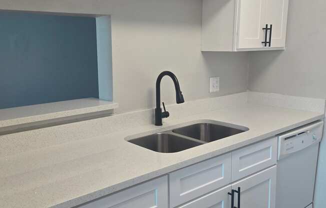 an empty kitchen with white cabinets and a sink