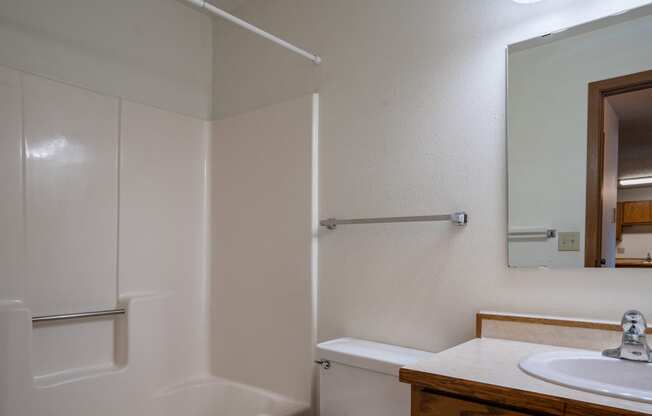 a bathroom with a sink and a shower and a mirror. Fargo, ND Southview Village Apartments