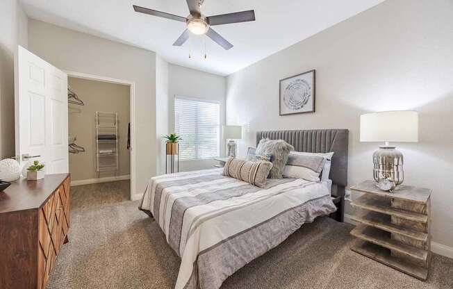A bedroom with a bed, nightstand, and a ceiling fan.