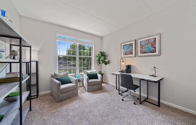 A room with a desk, chairs, and a window.