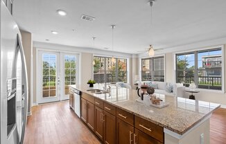 a kitchen with a large island next to a living room at The Dorset, Kansas City, MO