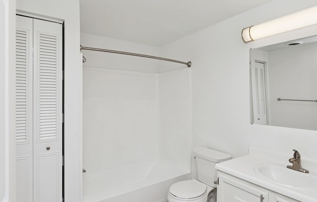 A white bathroom with a toilet, sink, and shower.