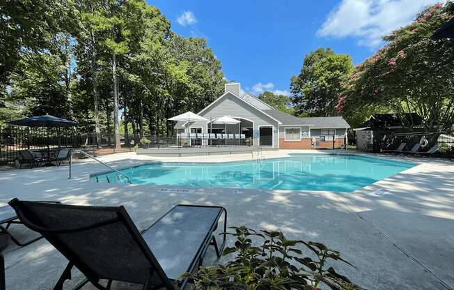 a swimming pool with chairs and a house in the background