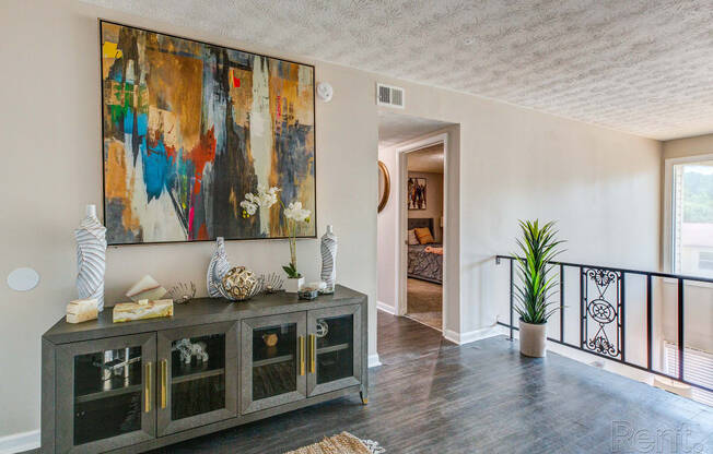 a living room with a large painting on the wall and a cabinet