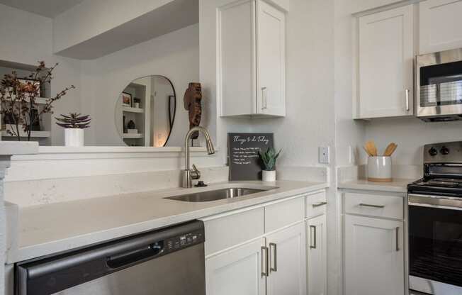 a kitchen with white cabinets and stainless steel appliances and a sink