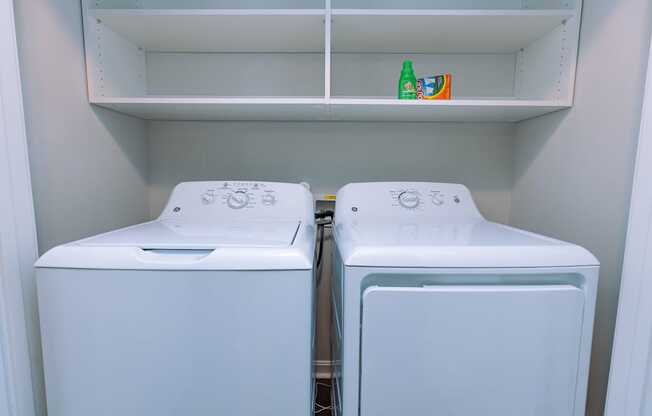 Two white washing machines in a laundry room.