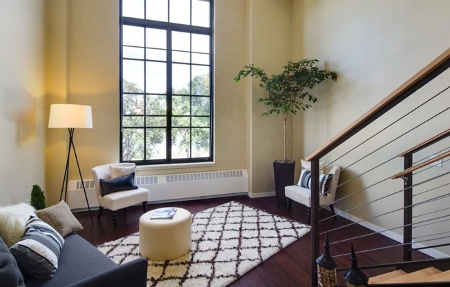 a living room with a staircase and a large window