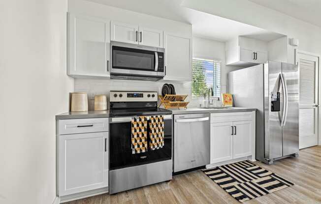 a kitchen with stainless steel appliances and white cabinetry