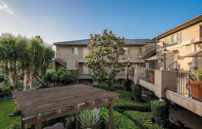 A wooden deck is in the middle of a grassy area with a building in the background.