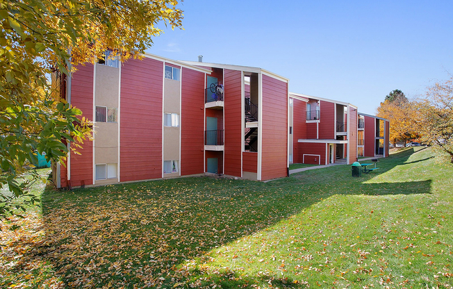 Charming red-brick apartment complex with lush green lawns and vibrant autumn trees.